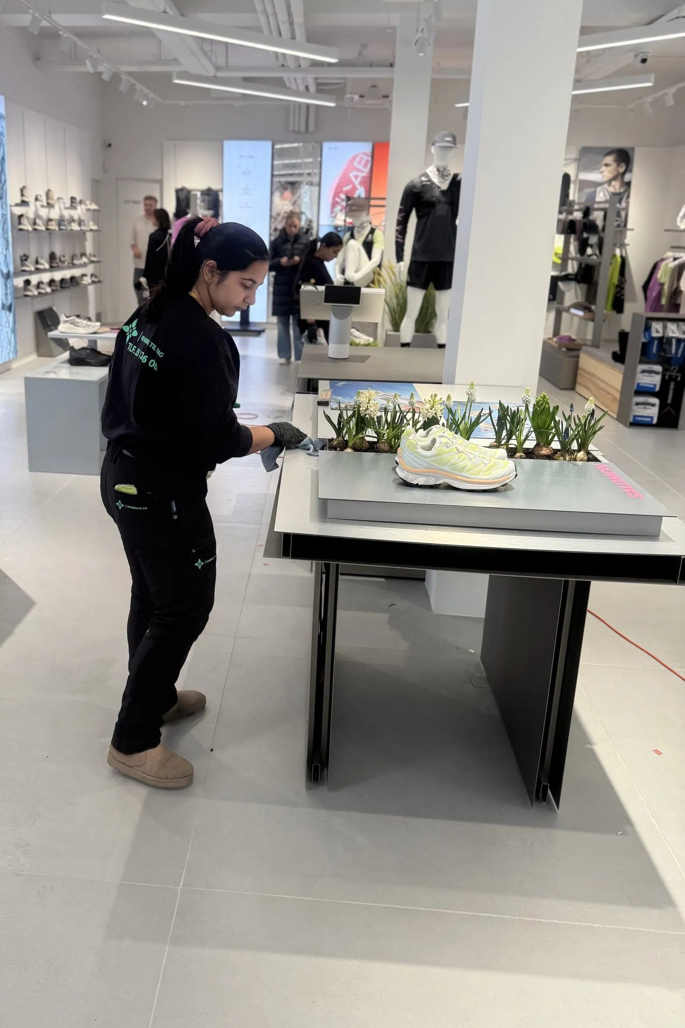 Medarbejder fra Rengøring Til Dig tørrer et udstillingsbord af i en butik